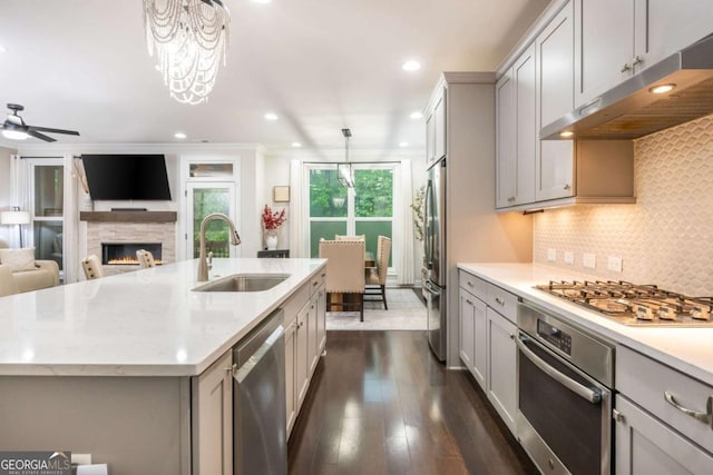 kitchen with a sink, stainless steel appliances, under cabinet range hood, gray cabinetry, and recessed lighting