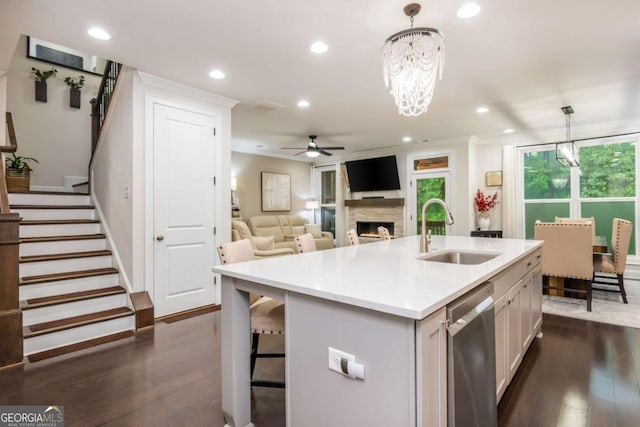 kitchen featuring a sink, dishwasher, ceiling fan, a lit fireplace, and light countertops