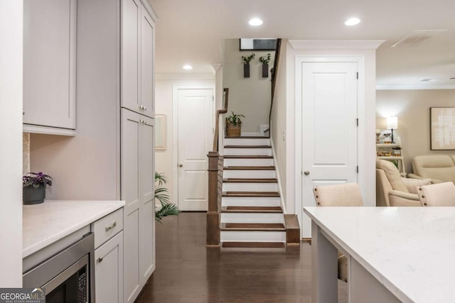 stairway with ornamental molding, recessed lighting, and wood finished floors
