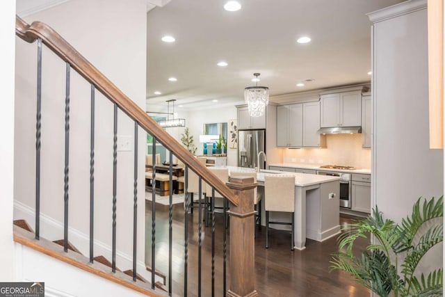 kitchen with light countertops, gray cabinets, stainless steel appliances, recessed lighting, and a kitchen breakfast bar
