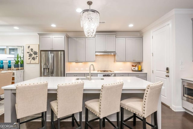 kitchen featuring stainless steel appliances, a sink, gray cabinets, under cabinet range hood, and light countertops