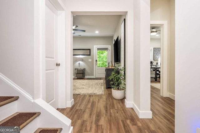 hallway with wood finished floors, baseboards, and stairs