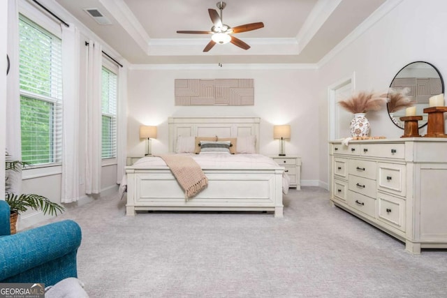 bedroom with a tray ceiling, light colored carpet, baseboards, crown molding, and a ceiling fan