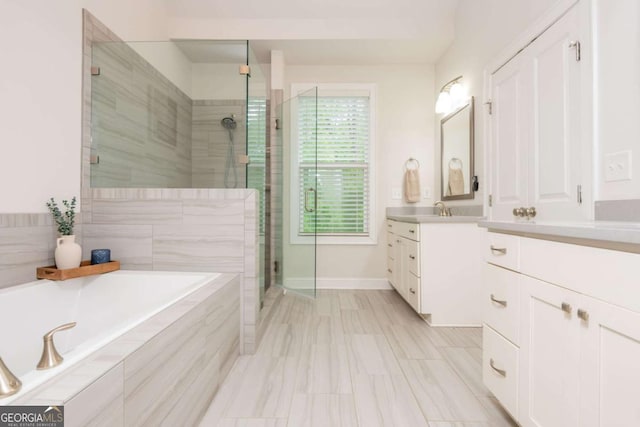 bathroom with a shower stall, a bath, vanity, and baseboards