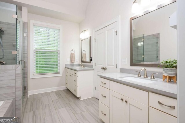 bathroom with a shower stall, two vanities, and baseboards