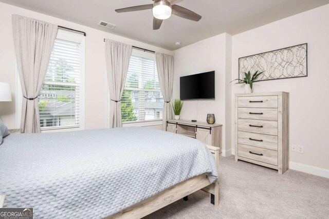 bedroom featuring baseboards, light colored carpet, and a ceiling fan