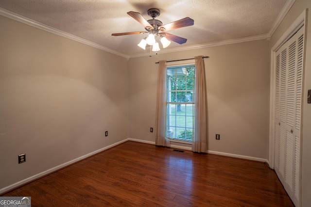 spare room featuring wood finished floors, a ceiling fan, ornamental molding, a textured ceiling, and baseboards