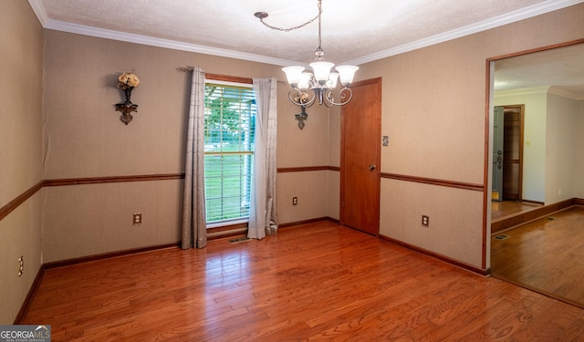 unfurnished dining area featuring a chandelier, wood finished floors, baseboards, and crown molding