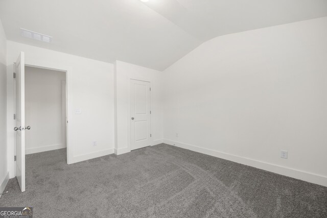 unfurnished bedroom with lofted ceiling, carpet flooring, and baseboards