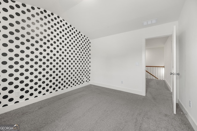 carpeted spare room featuring vaulted ceiling and baseboards