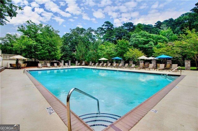 28106 Plantation Dr NE, Atlanta, GA 30324 - community pool with fence, a patio, and view of wooded area