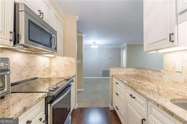 28106 Plantation Dr NE, Atlanta, GA 30324 - kitchen with stainless steel appliances, decorative backsplash, light stone counters, baseboards, and ornamental molding