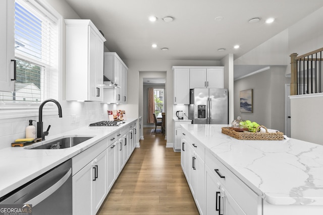 2436 Hidden Creek Rd, Kennesaw, GA 30152 - kitchen with appliances with stainless steel finishes, light wood-type flooring, a center island, white cabinets, and backsplash
