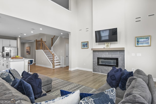 2436 Hidden Creek Rd, Kennesaw, GA 30152 - living room featuring light wood finished floors, stairs, a tile fireplace, recessed lighting, and a high ceiling