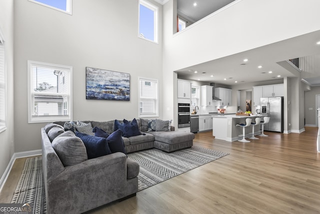 2436 Hidden Creek Rd, Kennesaw, GA 30152 - living room featuring a towering ceiling, light wood-type flooring, and baseboards