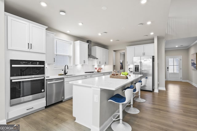 2436 Hidden Creek Rd, Kennesaw, GA 30152 - kitchen with stainless steel appliances, wall chimney range hood, a center island, a kitchen bar, and white cabinets