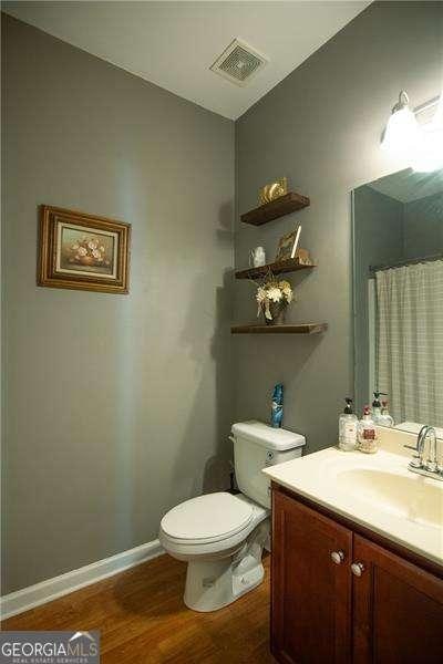 4271 Haywater Cv, Buford, GA 30519 - bathroom with wood finished floors, vanity, baseboards, toilet, and a shower with curtain