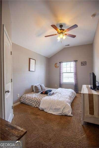 4271 Haywater Cv, Buford, GA 30519 - carpeted bedroom featuring lofted ceiling, ceiling fan, and baseboards