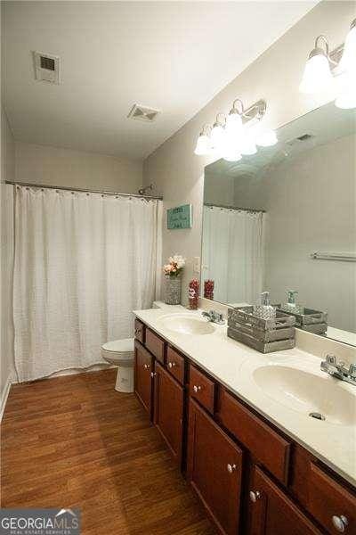 4271 Haywater Cv, Buford, GA 30519 - bathroom with wood finished floors, toilet, and double vanity