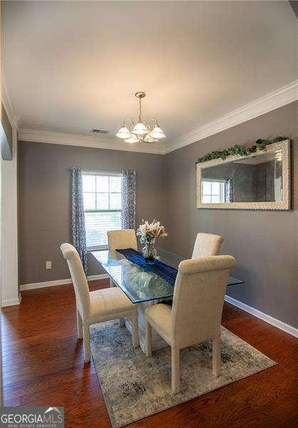 4271 Haywater Cv, Buford, GA 30519 - dining room with a chandelier, wood finished floors, crown molding, and plenty of natural light