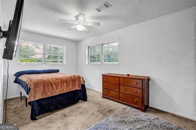 carpeted bedroom featuring baseboards, ceiling fan, and a textured ceiling