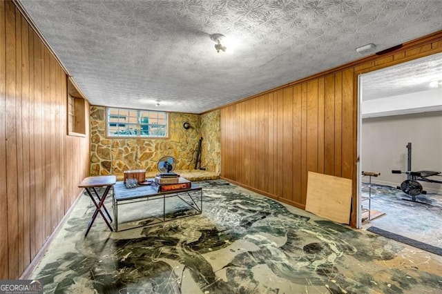 sitting room featuring wooden walls, baseboards, and a textured ceiling