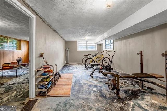 workout room featuring a textured ceiling and baseboards