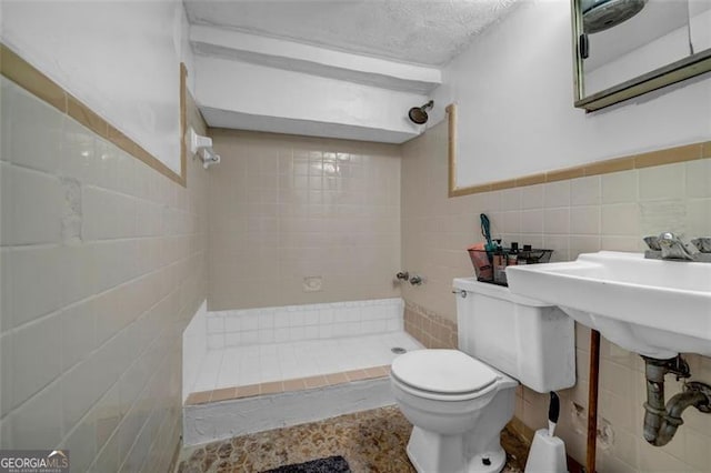 bathroom with tile walls, a stall shower, and toilet