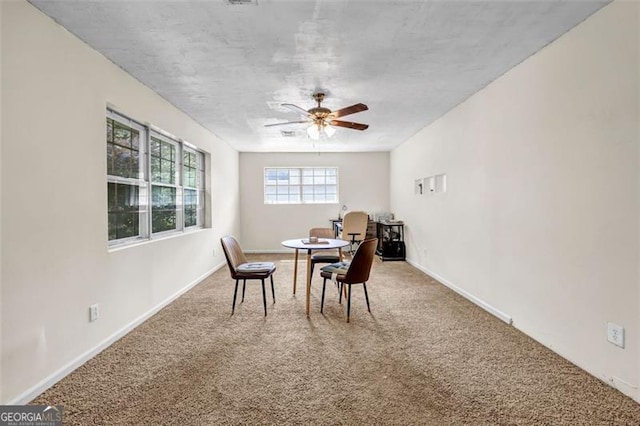 carpeted dining room with a ceiling fan and baseboards