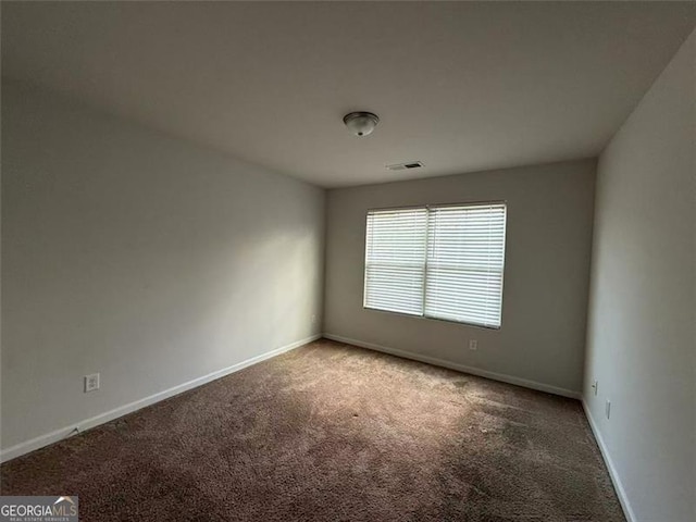 spare room featuring carpet flooring and baseboards