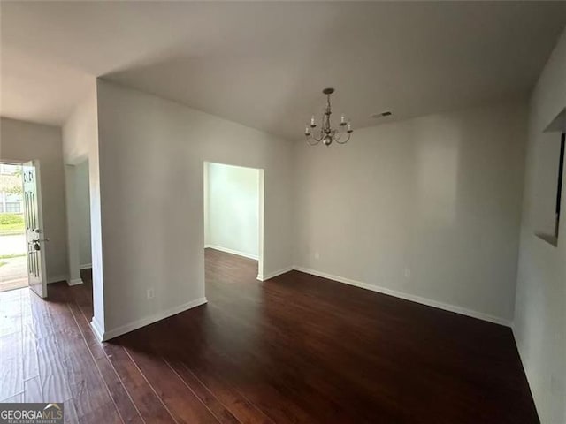 unfurnished dining area featuring a chandelier, dark wood finished floors, and baseboards