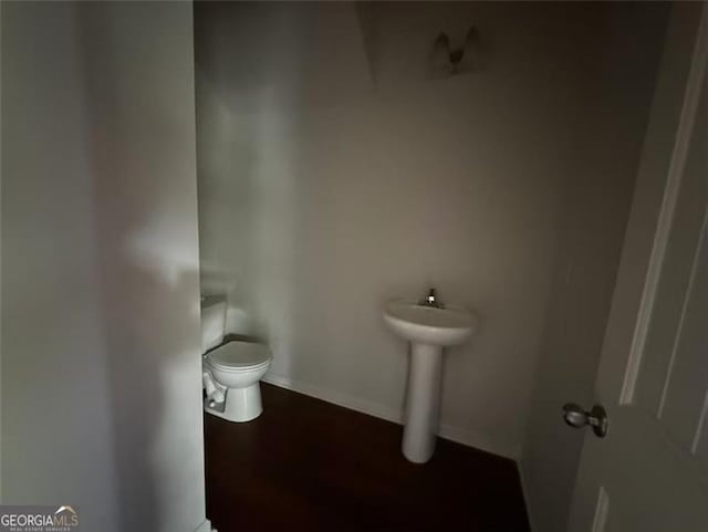 bathroom featuring toilet, baseboards, and a sink