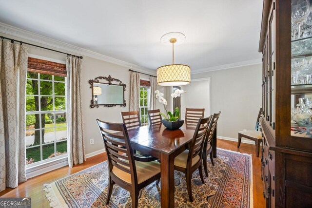 dining area featuring light wood-type flooring, ornamental molding, and baseboards
