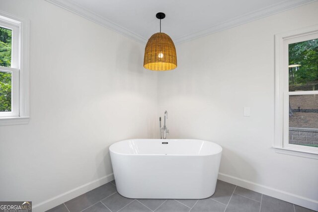 bathroom with baseboards, a freestanding tub, tile patterned flooring, and crown molding