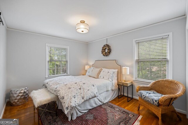 bedroom featuring crown molding, wood finished floors, and baseboards