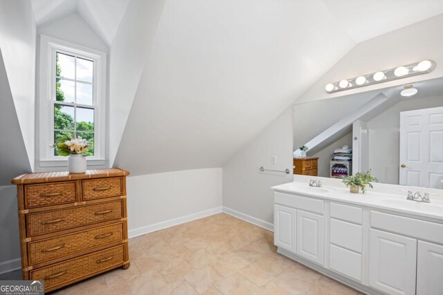 bathroom featuring vaulted ceiling, double vanity, and baseboards