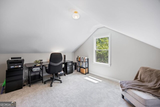 carpeted office with lofted ceiling and baseboards