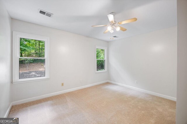 unfurnished room featuring healthy amount of natural light, light colored carpet, and baseboards