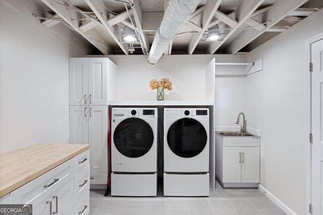 laundry area with washing machine and clothes dryer, cabinet space, and light tile patterned flooring