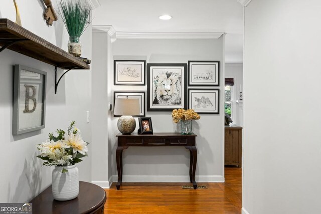 corridor featuring wood finished floors, baseboards, ornamental molding, and recessed lighting