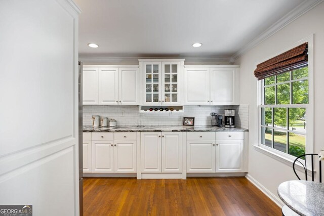 bar featuring dark wood-style flooring, decorative backsplash, ornamental molding, baseboards, and recessed lighting