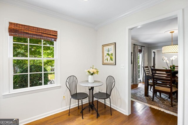 dining room featuring wood finished floors, crown molding, and baseboards