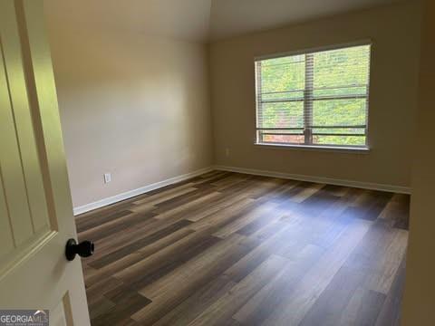 1307 Clarecastle Ln, Buford, GA 30519 - spare room with wood finished floors, baseboards, and vaulted ceiling