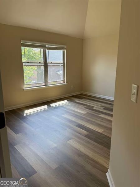 1307 Clarecastle Ln, Buford, GA 30519 - spare room with wood finished floors, vaulted ceiling, and baseboards