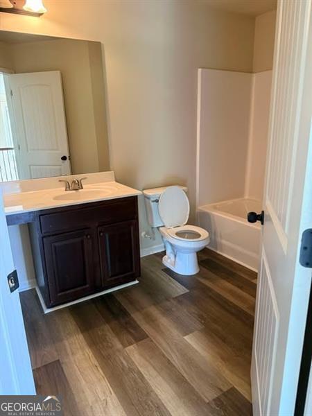 1307 Clarecastle Ln, Buford, GA 30519 - bathroom featuring wood finished floors, toilet, vanity, and tub / shower combination