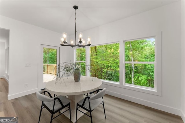 dining space featuring a chandelier, baseboards, and wood finished floors