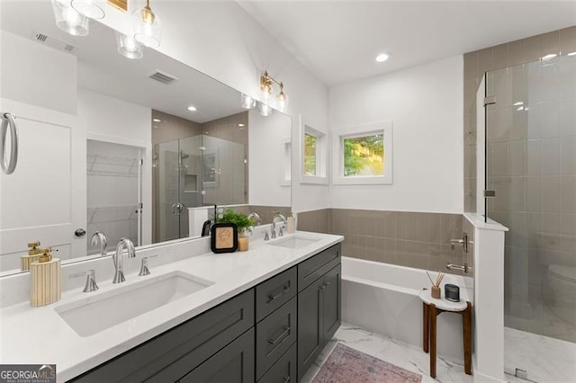 bathroom with marble look tiles, a shower stall, double vanity, a garden tub, and recessed lighting