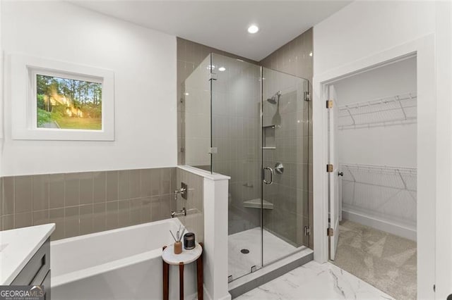 bathroom featuring a stall shower, a garden tub, a walk in closet, recessed lighting, and marble look tiles