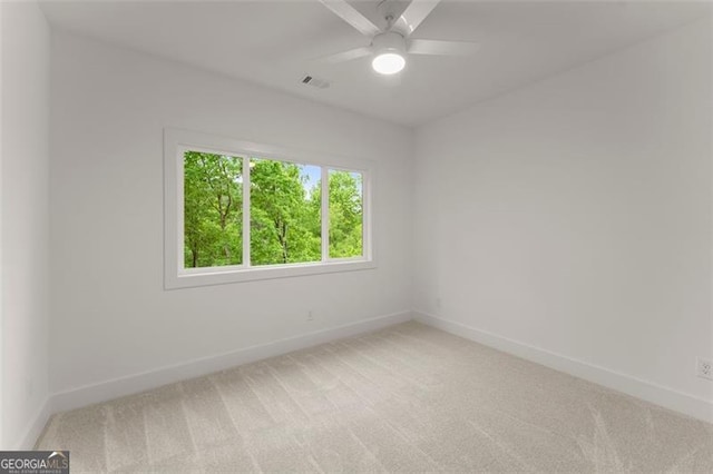 spare room featuring baseboards, light colored carpet, and a ceiling fan