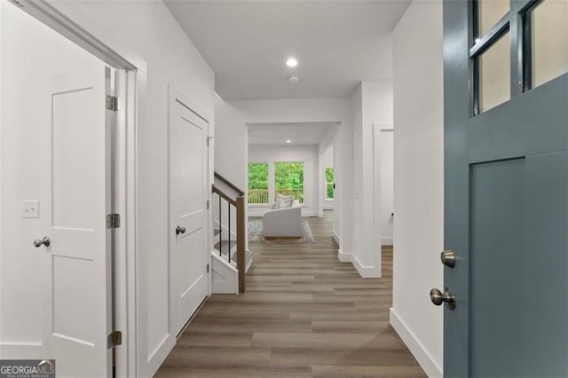 hallway featuring baseboards, wood finished floors, and recessed lighting
